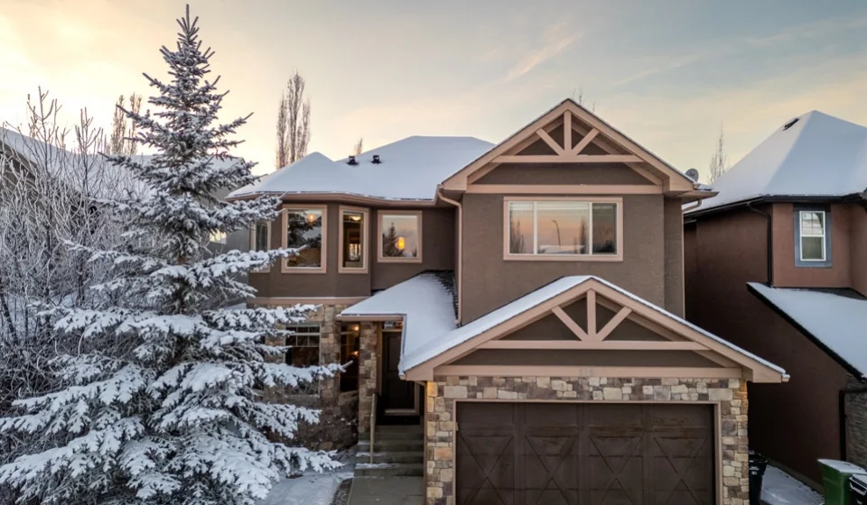 A snow-covered family home in Aspen Woods at dusk